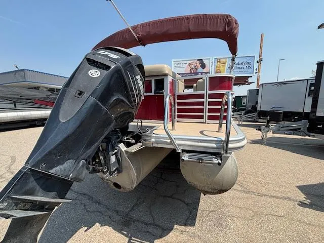 Slide: The Image of 2012 Bennington R25 pontoon boat with outboard motor, parked outdoors under clear sky. - 4
