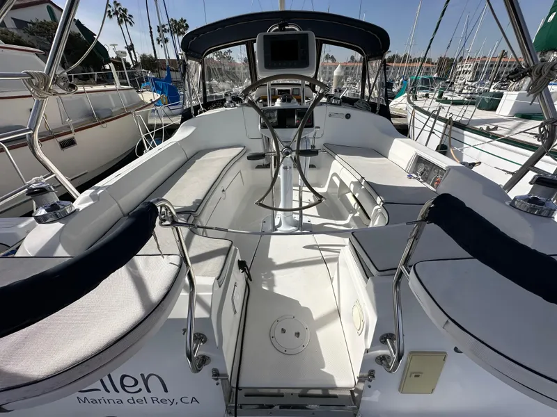 Slide: The Image of 2008 Hunter 38 sailboat cockpit with seating, steering wheel, and marina view. - 22