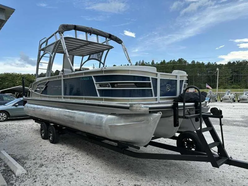 Slide: The Image of 2023 Godfrey AquaPatio 255 SDC pontoon boat on trailer, parked outdoors. - 1
