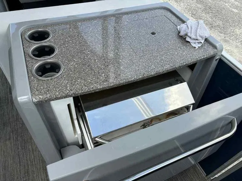 Slide: The Image of 2023 Godfrey AquaPatio 255 SDC boat kitchen area with countertop and cup holders. - 11