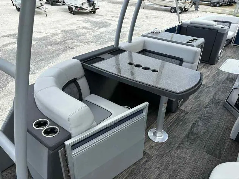 Slide: The Image of 2023 Godfrey AquaPatio 255 SDC boat interior with seating and table, featuring cup holders. - 16