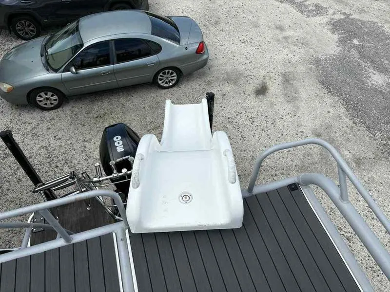 Slide: The Image of 2023 Godfrey AquaPatio 255 SDC boat with slide, parked near cars on gravel. - 26