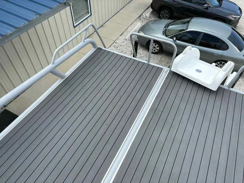 Slide: The Image of 2023 Godfrey AquaPatio 255 SDC boat deck with slide, parked near cars. - 8