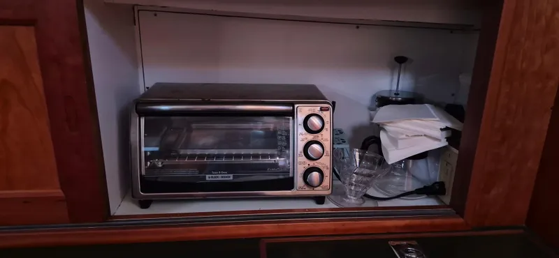 Slide: The Image of Toaster oven and kitchen items in a cabinet on a 1997 Able 44 Downeast Express Cruiser. - 15