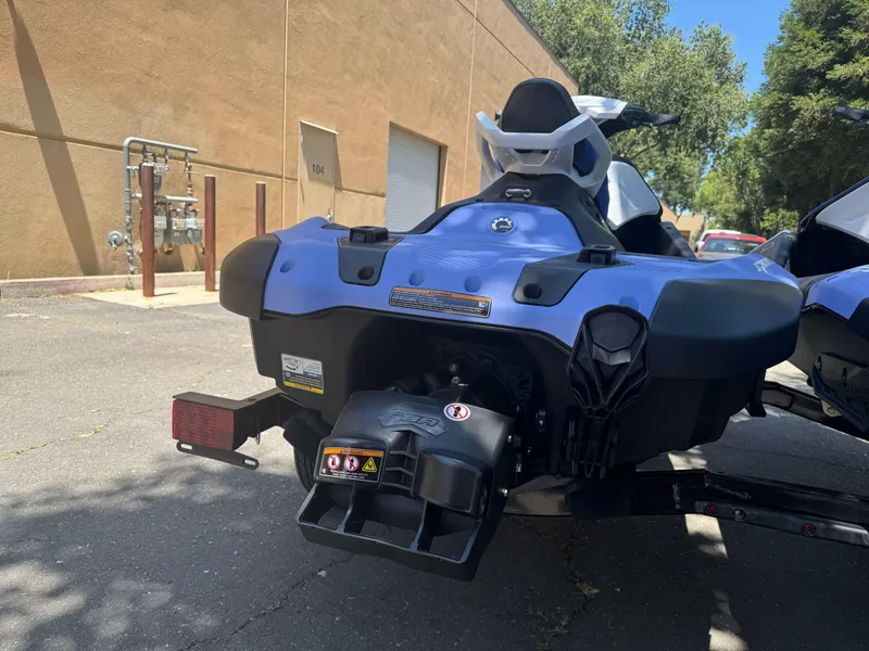 Slide: The Image of 2024 Sea-Doo Spark 2up jet ski parked outdoors, rear view, blue and black design. - 2