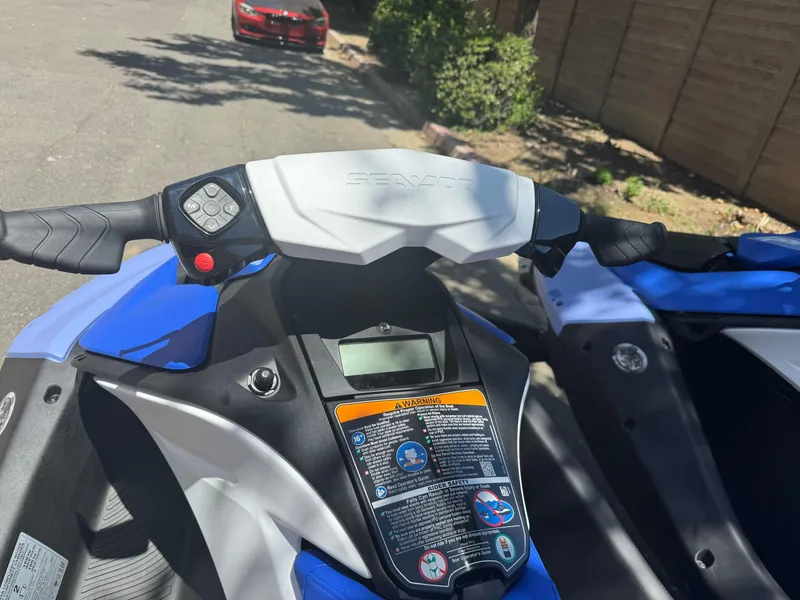 Slide: The Image of 2024 Sea-Doo Spark 2up jet ski handlebars and controls, parked outdoors. - 3