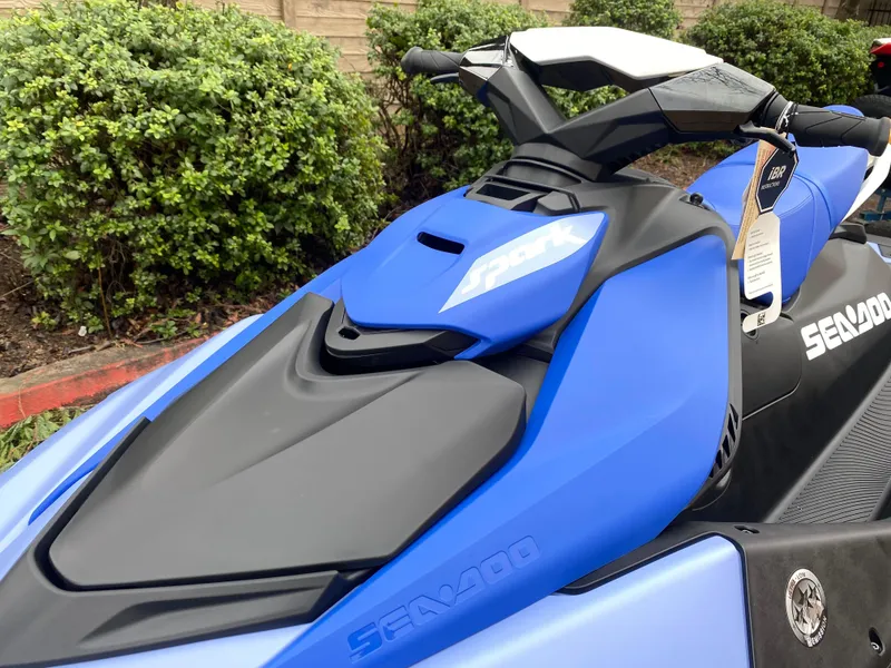 Slide: The Image of 2024 Sea-Doo Spark 3up in blue, parked outdoors with greenery background. - 2