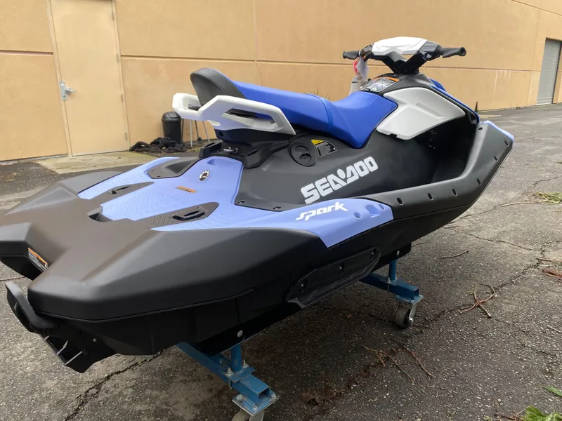 Slide: The Image of 2024 Sea-Doo Spark 3up jet ski in blue and black, parked outdoors. - 9