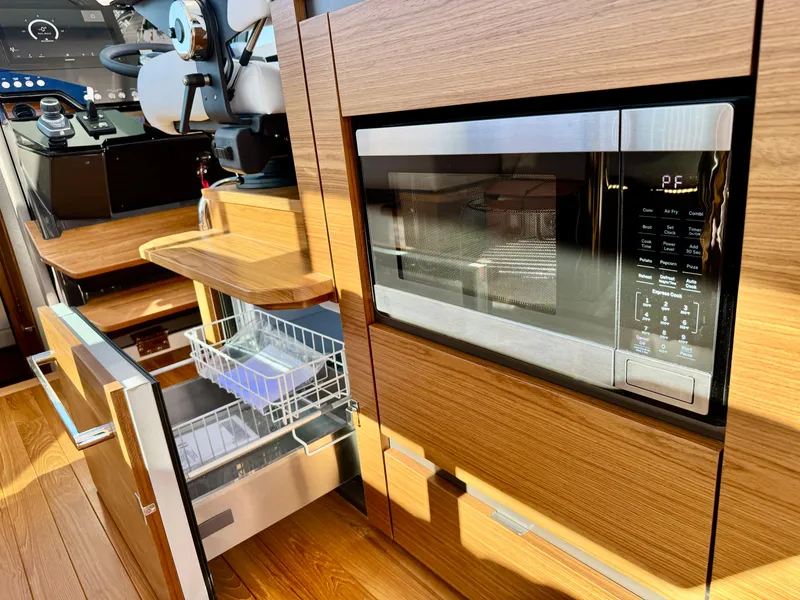 Slide: The Image of 2025 Tiara Yachts 43 LE interior with microwave and dishwasher in wooden cabinetry. - 21