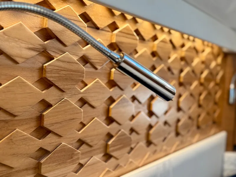 Slide: The Image of Wooden geometric wall design with a sleek metal light fixture on a 2025 Tiara Yachts 43 LE. - 47