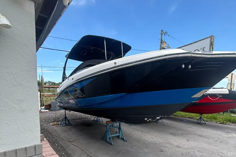 The Image of 2017 Monterey M65 boat on stands, blue and black hull, outdoor setting. - 0