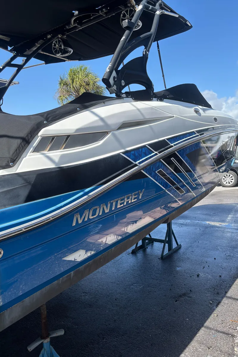 Slide: The Image of 2017 Monterey M65 boat on stands, blue and white design, sunny day background. - 13