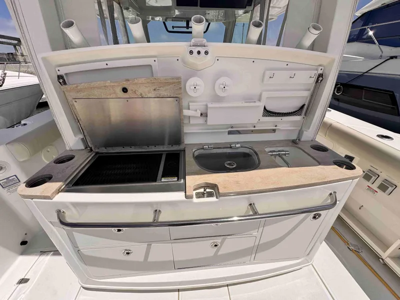 Slide: The Image of 2018 Boston Whaler 350 Outrage boat kitchen with grill, sink, and storage compartments. - 13