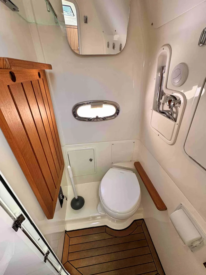 Slide: The Image of 2018 Boston Whaler 350 Outrage boat bathroom with wooden accents and compact design. - 30