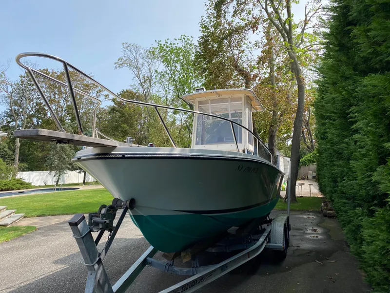 Slide: The Image of 1982 Mako 23 Inboard Diesel boat on trailer, surrounded by trees and driveway. - 14