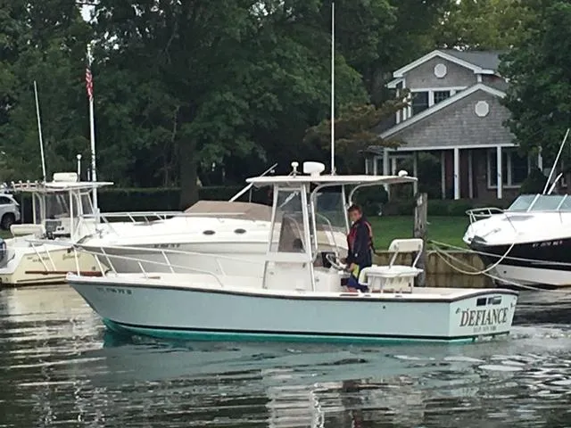 Slide: The Image of 1982 Mako 23 Inboard Diesel boat named "Defiance" on calm water near a dock. - 2