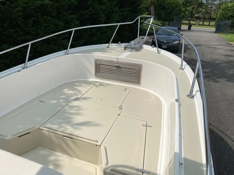 Slide: The Image of 1982 Mako 23 Inboard Diesel boat with open deck and railing, parked near trees. - 21