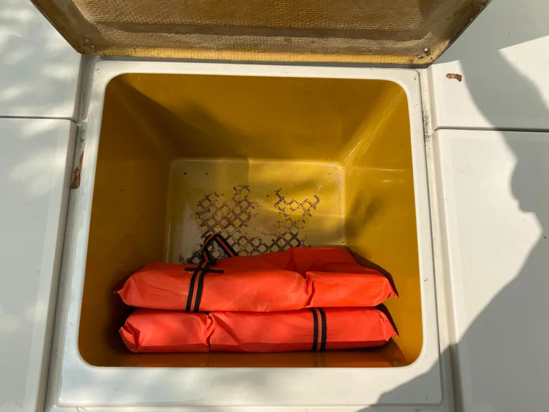 Slide: The Image of Open storage compartment on 1982 Mako 23 Inboard Diesel boat with orange life jackets. - 23