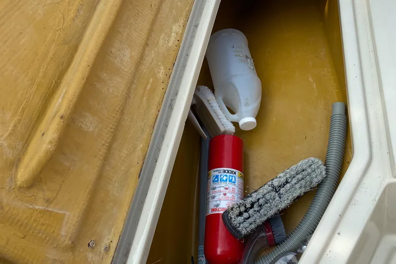 Slide: The Image of Storage compartment of 1982 Mako 23 Inboard Diesel with fire extinguisher and cleaning supplies. - 39