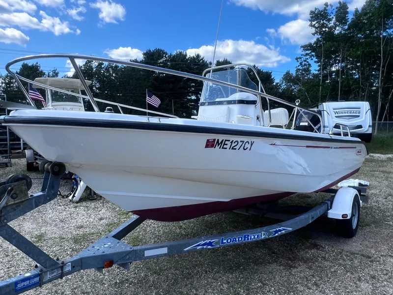 Slide: The Image of 2003 Boston Whaler 180 Dauntless boat on trailer, parked outdoors under blue sky. - 2