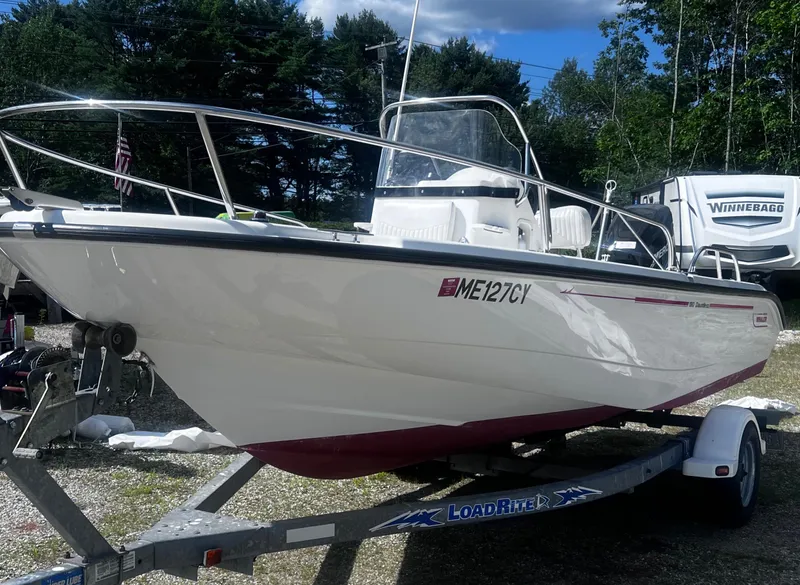 Slide: The Image of 2003 Boston Whaler 180 Dauntless boat on trailer, parked outdoors with trees in background. - 4