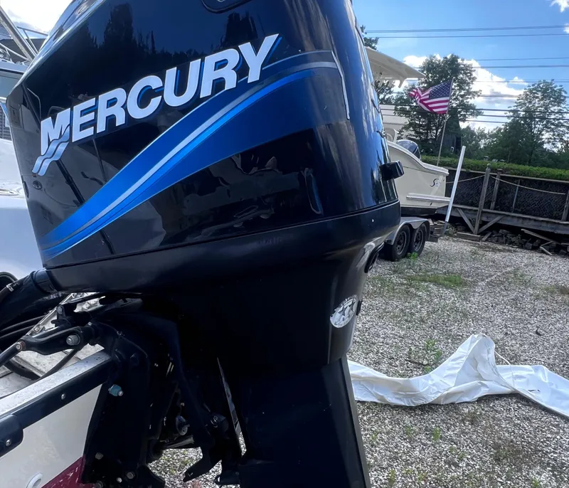 Slide: The Image of Mercury outboard motor on a 2003 Boston Whaler 180 Dauntless, parked on gravel. - 7