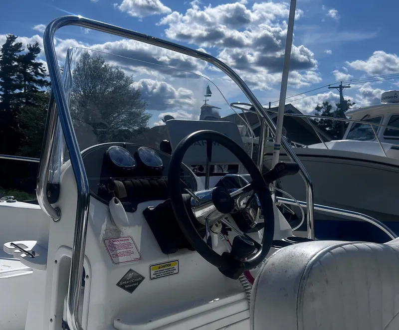Slide: The Image of 2003 Boston Whaler 180 Dauntless boat console with steering wheel and gauges under a cloudy sky. - 8