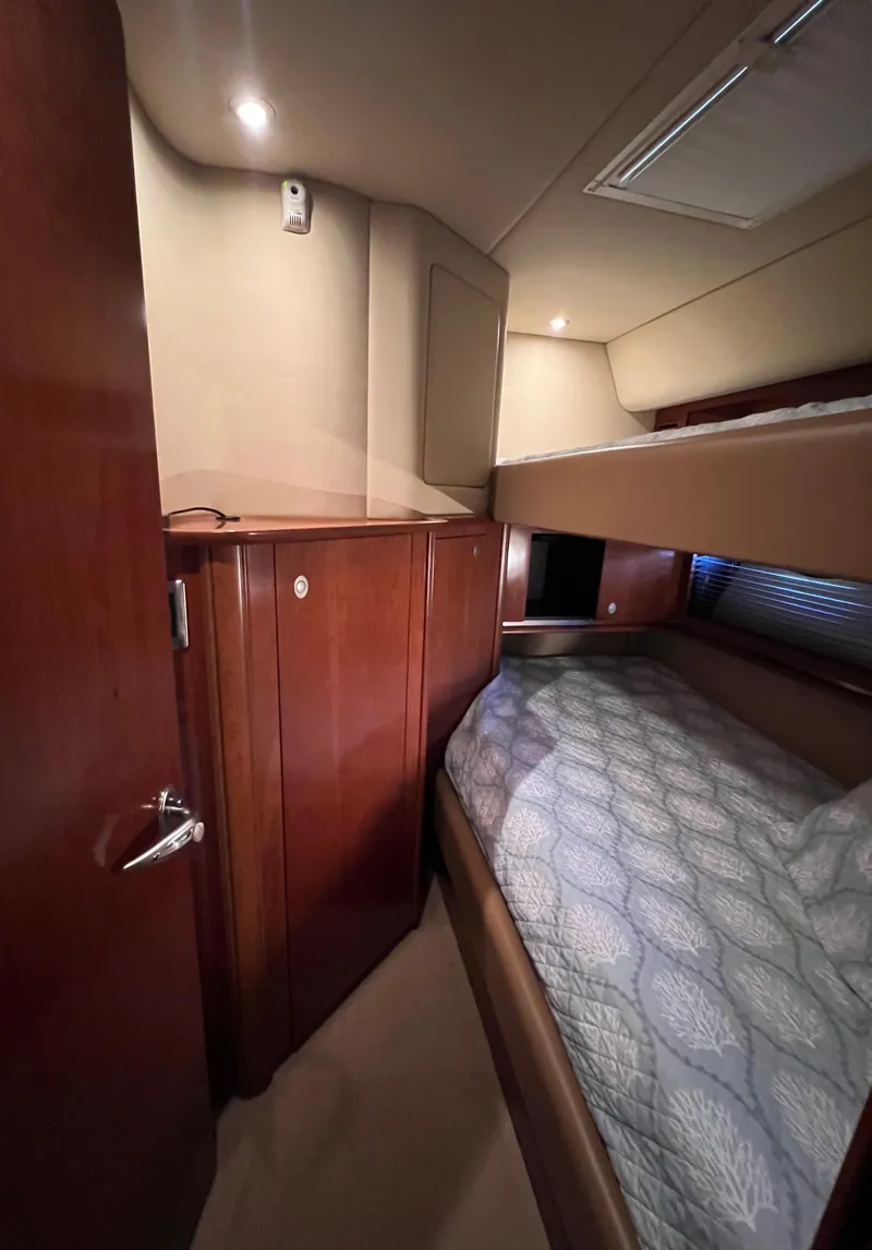 Slide: The Image of 2005 Sea Ray 500 Sundancer cabin interior with wooden cabinetry and cozy bedding. - 20