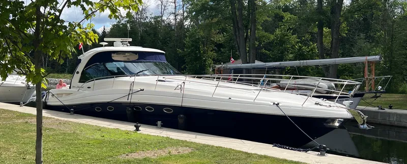 Slide: The Image of 2005 Sea Ray 500 Sundancer yacht docked by a lush, green shoreline. - 4