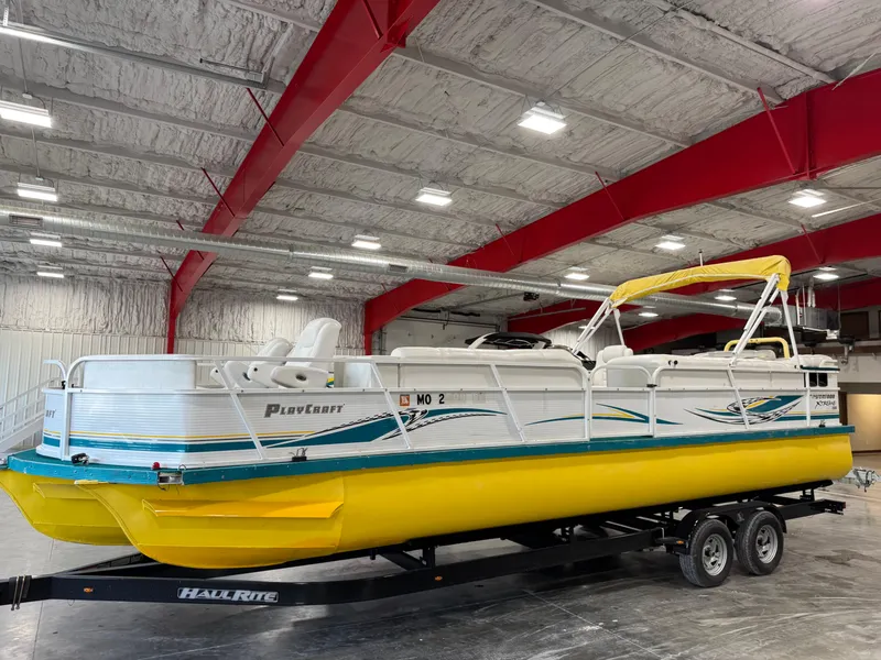 Slide: The Image of 2004 PlayCraft 2800 Powertoon boat with yellow pontoons in a warehouse. - 1
