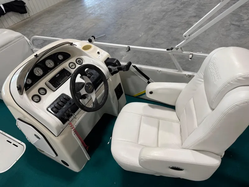 Slide: The Image of 2004 PlayCraft 2800 Powertoon boat cockpit with steering wheel and white captain's chair. - 13