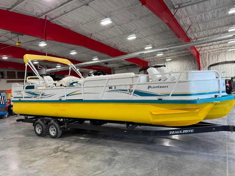 Slide: The Image of 2004 PlayCraft 2800 Powertoon boat with yellow hull on trailer in indoor storage. - 2