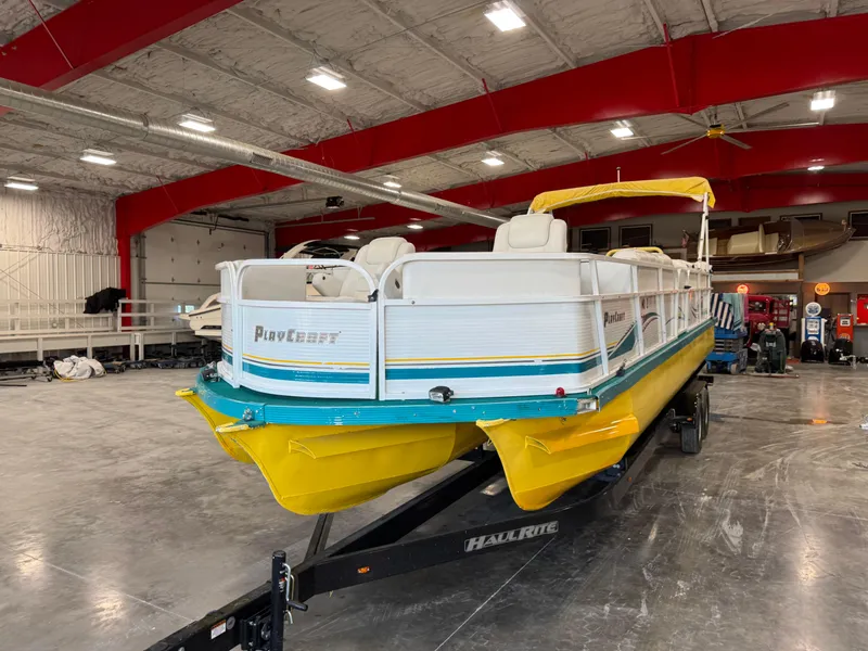 Slide: The Image of 2004 PlayCraft 2800 Powertoon boat with yellow pontoons in a spacious indoor storage facility. - 5