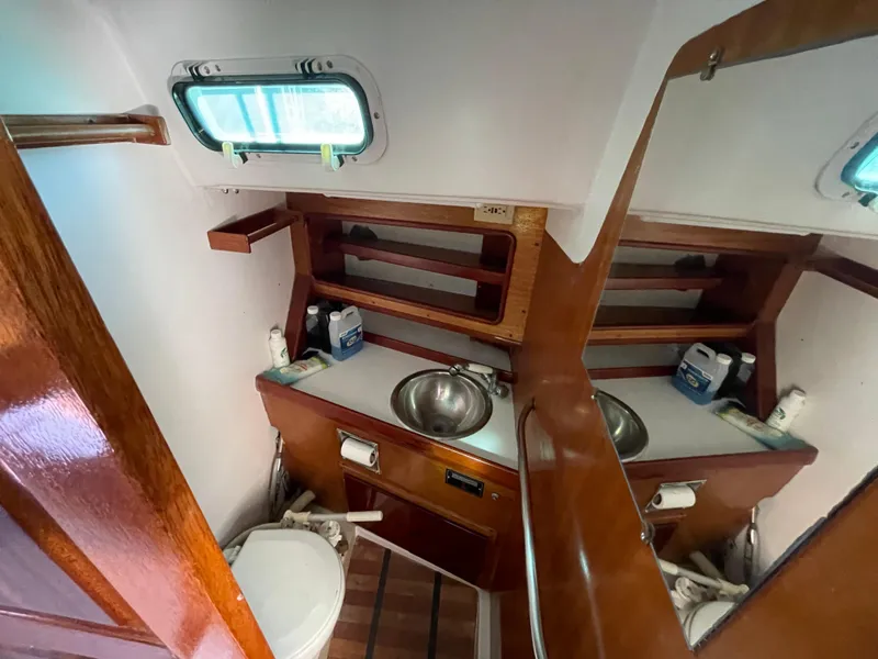 Slide: The Image of Compact wooden boat bathroom with sink, mirror, and toilet in a 1964 CAL 40 model. - 7