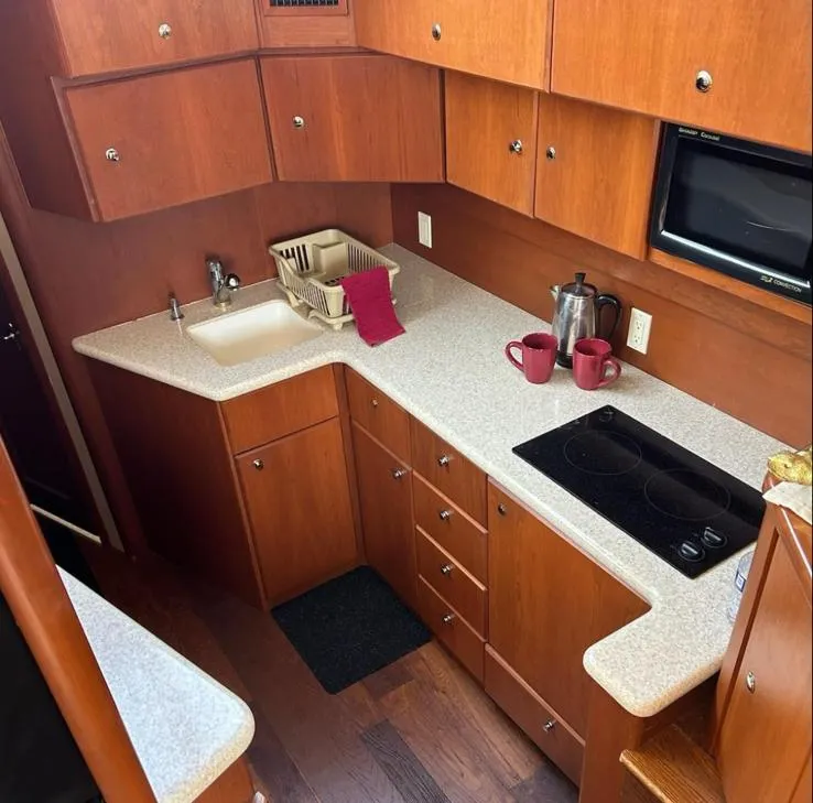 Slide: The Image of 2005 Silverton 42 Convertible yacht kitchen with wooden cabinets, sink, stove, and countertop accessories. - 4