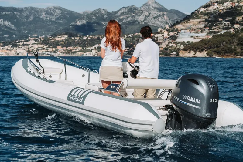 Slide: The Image of 2026 Novurania DL 550 boat cruising on scenic coastal waters with two passengers. - 1