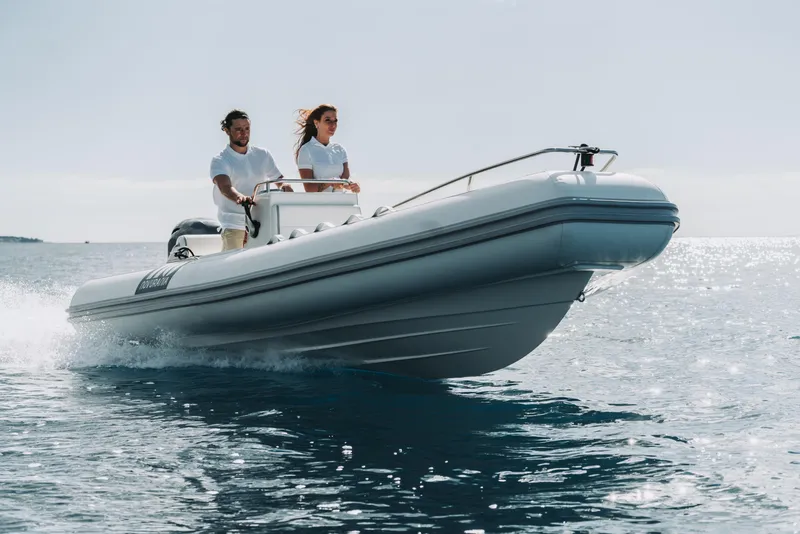 Slide: The Image of Novurania DL 550 boat cruising on open water, 2026 model, with two people onboard. - 10