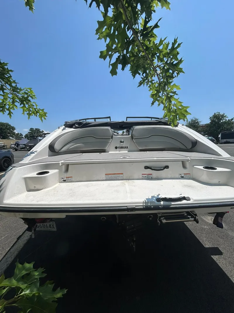 Slide: The Image of 2024 Yamaha Boats SX190 rear view with swim platform and seating under a clear sky. - 8