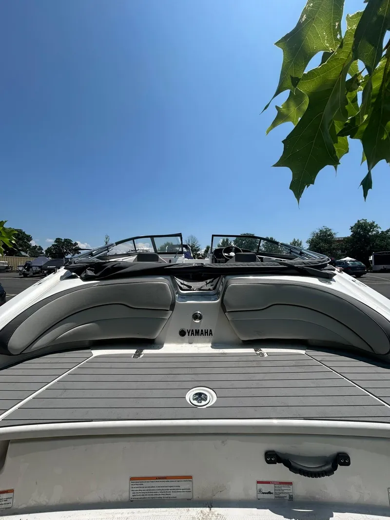 Slide: The Image of 2024 Yamaha SX190 boat, rear view, under clear blue sky with green leaves. - 9