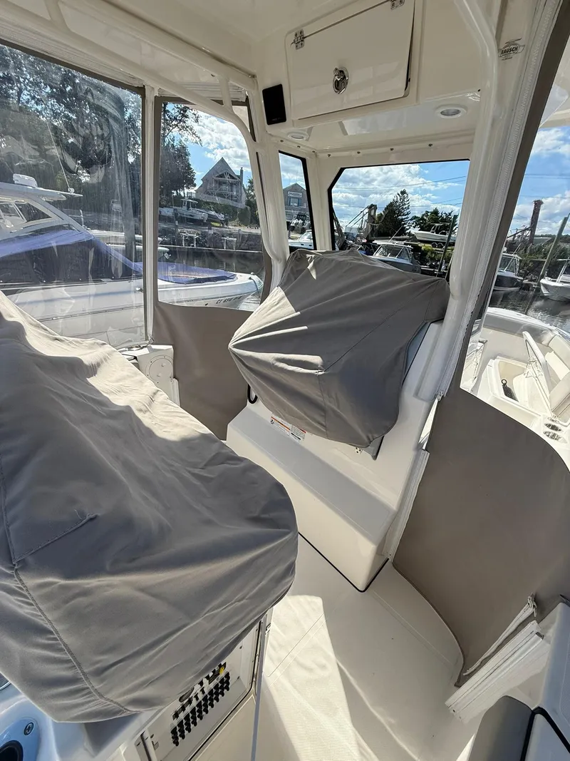 Slide: The Image of 2023 Pursuit S 268 Sport boat interior with covered seats and clear windows. - 26