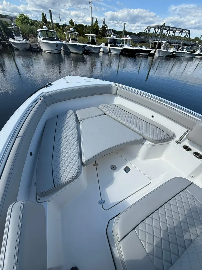 Slide: The Image of 2023 Pursuit S 268 Sport boat interior with cushioned seating, docked in a marina. - 4