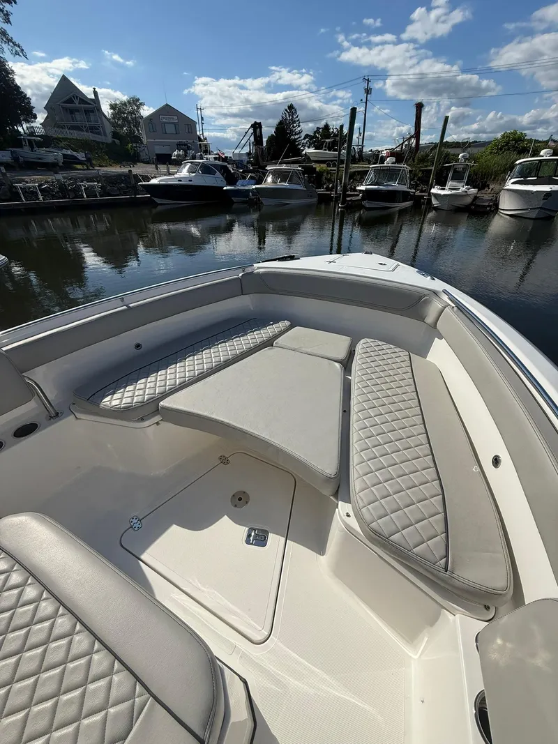 Slide: The Image of 2023 Pursuit S 268 Sport boat interior with cushioned seating, docked in a marina. - 5
