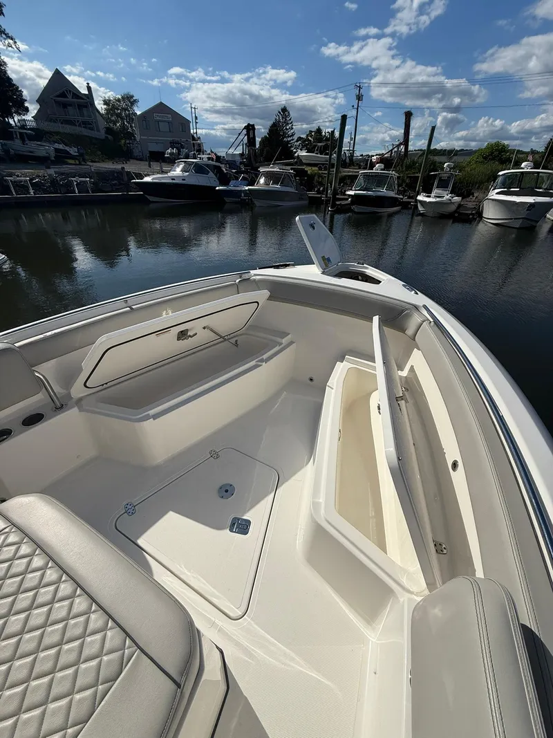 Slide: The Image of 2023 Pursuit S 268 Sport boat interior with open storage compartments at a marina. - 7