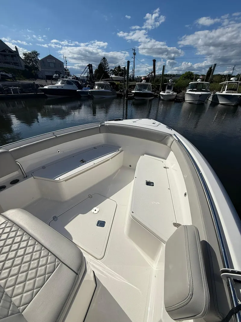 Slide: The Image of 2023 Pursuit S 268 Sport boat interior at marina, showcasing seating and storage. - 8