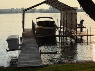 Slide: The Image of 2012 Sea Ray 270 SLX docked under a canopy on a serene lake. - 25
