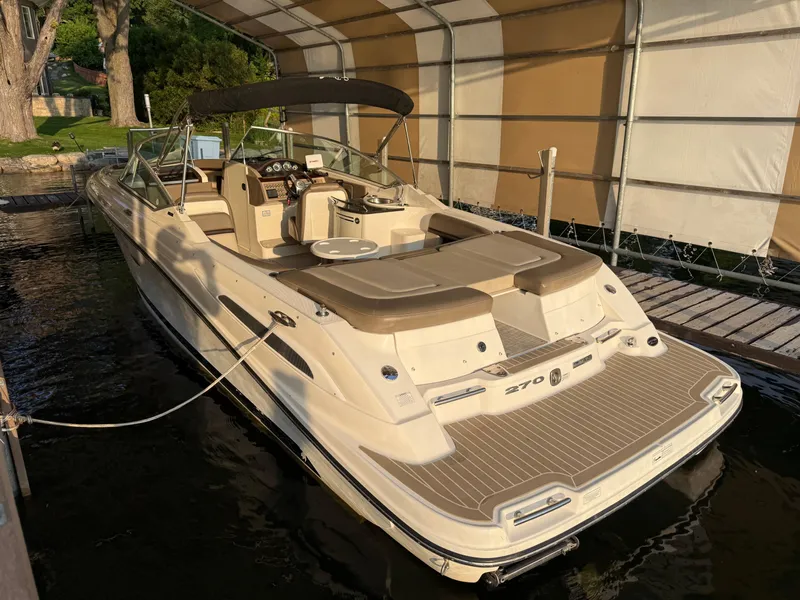 Slide: The Image of 2012 Sea Ray 270 SLX boat docked under a canopy, featuring a spacious deck and seating. - 4