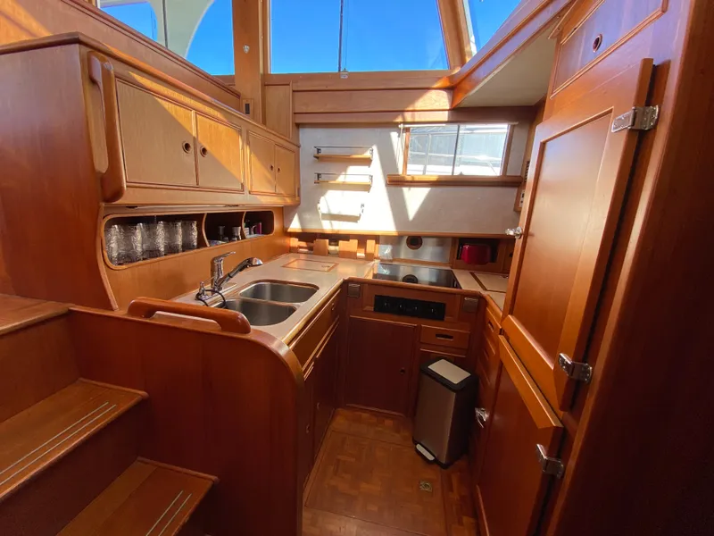 Slide: The Image of Interior of 1992 Grand Banks 46 Europa yacht, featuring a wooden kitchen with sink and stove. - 33