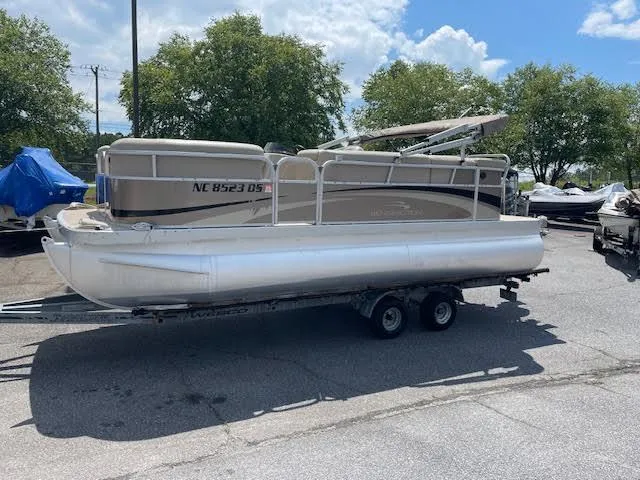 Slide: The Image of 2011 Bennington LSI pontoon boat on trailer, parked outdoors under a clear sky. - 1