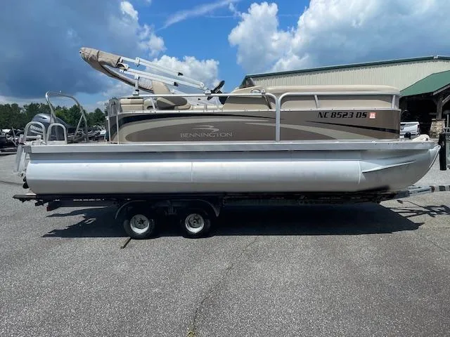 Slide: The Image of 2011 Bennington LSI pontoon boat on trailer under a cloudy sky. - 2