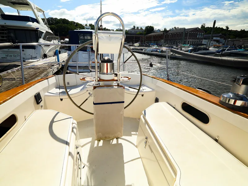 Slide: The Image of 1987 Sabre 36 Sloop cockpit with steering wheel, docked at marina under blue sky. - 17